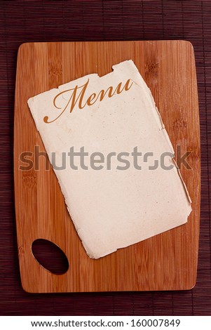 Ancient sheet menu on a wooden chopping board.