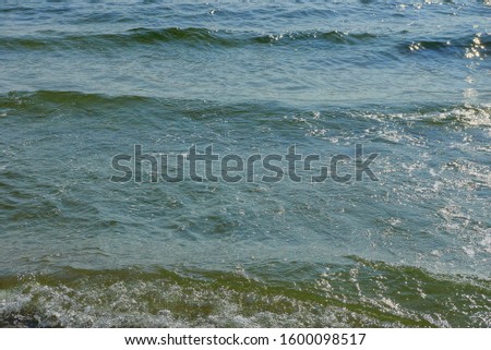 blue green water background from sea waves and white foam