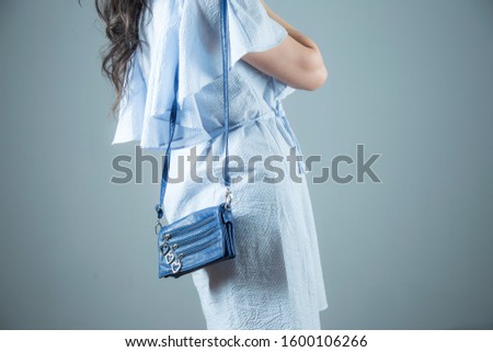 woman in blue dress and blue bag in studio