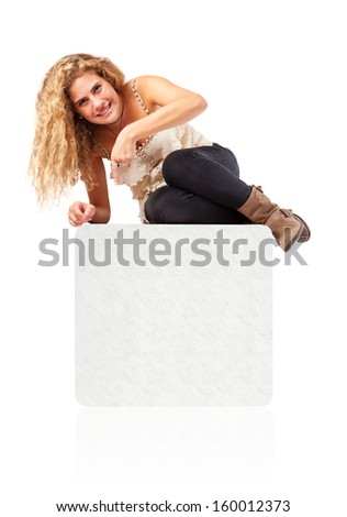 Woman sitting on blank empty box, pointing down at copy space.
