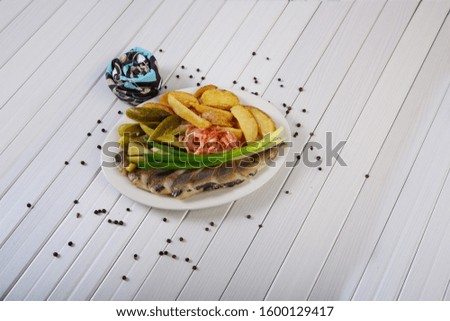 Delicious appetizer of pickles, potatoes, onions and salted fish all shot on a white background