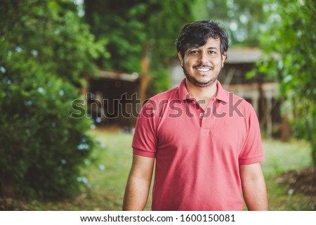 Portrait of smiling beautiful young male farmer. Man at farm in summer day. Gardening activity. Brazilian man.
