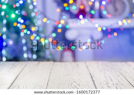 Wooden table in front of christmas blurred background. Empty old wooden table on blurred New Year's background in bokeh. Presentation table with blurry red blue yellow green lights in the background. 