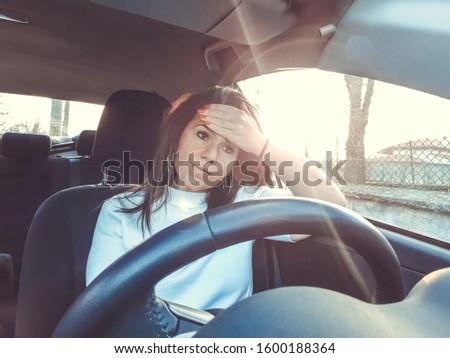 Beautiful woman  having a problem   with a car sitting inside holding her head with hands waiting for help