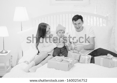 Happy family mom dad and son open Christmas presents on the bed. Christmas concept. New Year concept. Happy family. Winter holidays