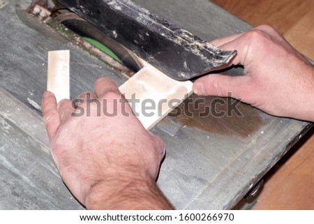 the process of cutting tile on a special tool with a diamond disk and wet sawing without dust. repair work performed by a specialist with a modern tool.