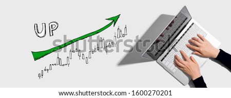 Market up trend chart with person using a laptop computer