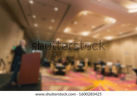 Abstract blur of speaker at podium talking to crowd at a conference. 