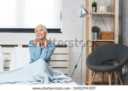 Senior woman suffering from nack pain and  numbness after sleep at home in bed. Old age, health problem and people concept