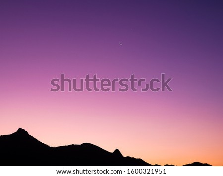 Beautiful sunset with mixed colors of red, blue, purple, yellow and orange. Mountains in the bottom, of the picture reflecting the gradient of colors 