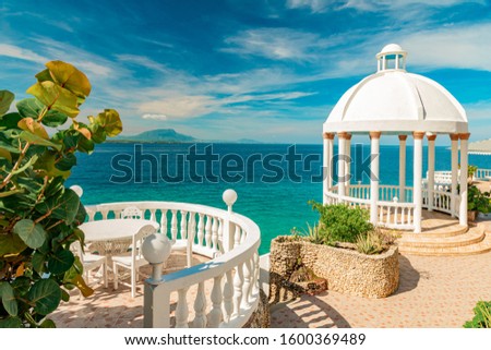 Beautiful white gazebo and tropical garden on Caribbean ocean background, summer mountain view , Sosua, Puerto Plata, Dominican Republic Royalty-Free Stock Photo #1600369489