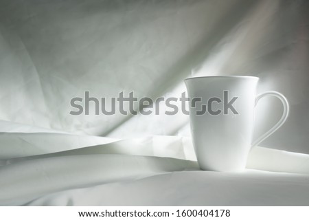 soft light still life of white ceramic cup or mug for coffee morning on fabric in classic renaissance painting style 