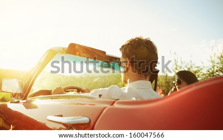 Couple driving convertible car enjoying a summer day at sunset Royalty-Free Stock Photo #160047566