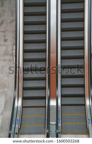An escalator with stainless steel and toughened glass handrails