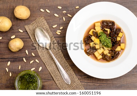 Soup with vegetable stock, potatoes and dried tomatoes in a white plate