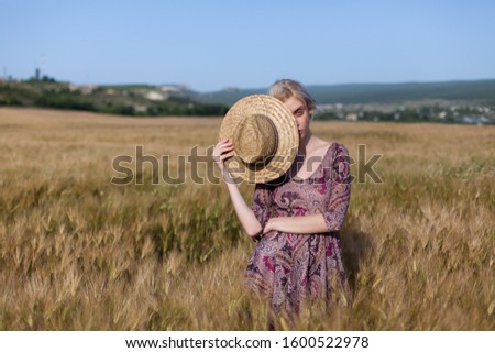 portrait of a beautiful fashionable blonde woman in a hat in a field of ripe wheat