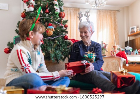 grandmother and grandson at home happy doing the Christmas tree and giving gifts in Christmas clothes