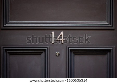 House number 14 with peephole on a dark wooden front door