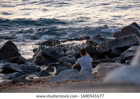 Photographer on the beach setting up the camera and waiting for a good moment for a landscape photography. Barcelona, Spain