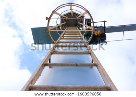 Metal ladder towards overhead crane with safety railing around.