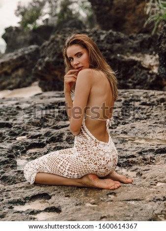 Young attractive woman with perfect body in knitted dress posing at tropical beach. Royalty-Free Stock Photo #1600614367