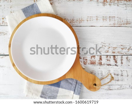 Round pizza boards, kitchen cloth and empty plate is cornered on the left with a white background from the top view.