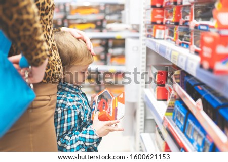 A little child with mother chooses a toy car in the store