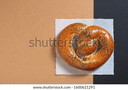 Pretzel with poppy on paper on a two-tone background, top view with copy space