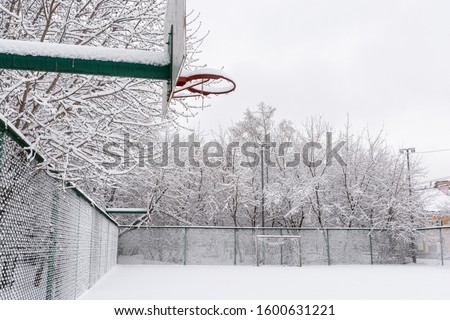 Snow covered basketball court. A lot of snow. The platform is empty. Basketball hoop.