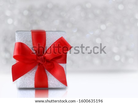 Decorative gift box with red bow. Concept of Valentine's day and international Women's day. Silver bokeh background for Copy space. 