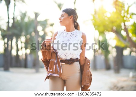 Young beautiful woman wearing jacket standing at the town park
