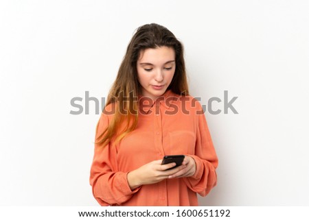 Young brunette girl over isolated white background sending a message with the mobile