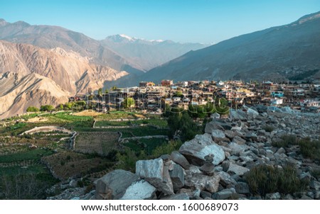 Nako village flanked by fields, high Himalayan mountains, and rocky footpath in the Spiti valley at sunrise in Himachal Pradesh, India. Royalty-Free Stock Photo #1600689073