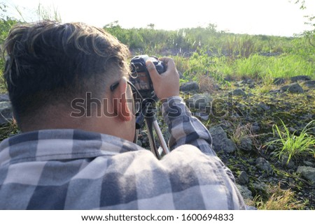 A man with a camera takes pictures of the landscape stretched out before him