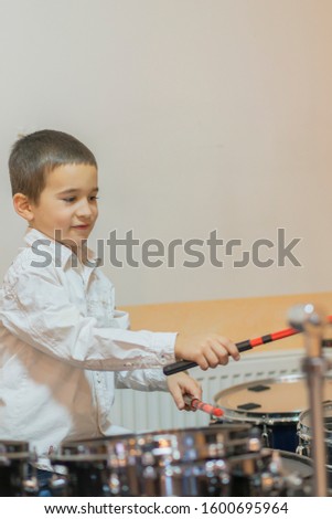 Boy drumming. boy in a white shirt plays the drums. vertical photo