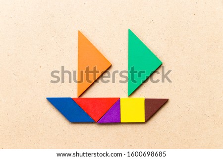 Color tangram in sailing boat shape on wood background (Concept for business start up or entrepreneur)