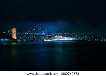 A cruise is passing under the Sydney harbour Bridge in a beautiful night in Sydney.