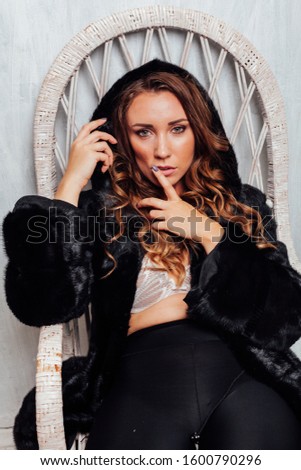 portrait of a beautiful fashionable woman with hair curls in a black fur coat