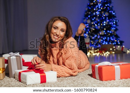 portrait of a beautiful woman at the Christmas tree with gifts for the new year