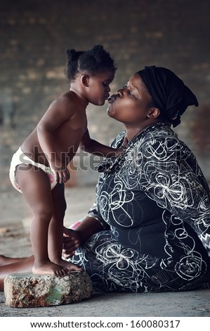 Loving mother kissing her baby girl rural african real people