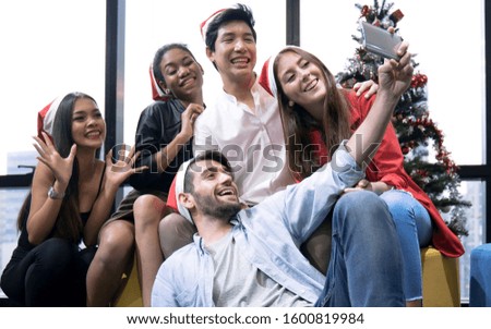 Group of young friends having fun at a Christmas and New Year's celebration, They are taking a selfie picture with a smartphone.