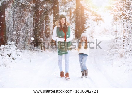 Young family for a walk. Mom and daughter are walking in a snowy park.