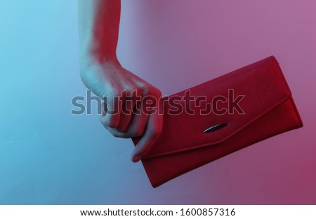 Female hand holds a leather wallet. Creative pop art pink blue neon color. Trendy gradient illumination. Night light