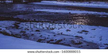 snow filled river banks with stones