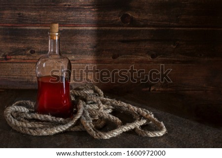 pirate bottle on the table, old rope, rum or whiskey in a transparent bottle, wooden background