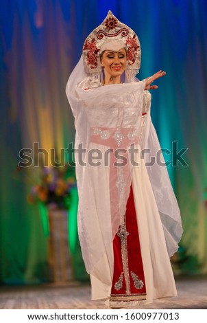 Young woman ballerina in a white suit with a crown on her head performs with a performance on stage in a theater