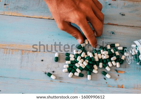 Close up of caucasian man hand taking chemichal pharmacy pills from a blue wood background - concept of drugs and disease - doctor and hopsital concept