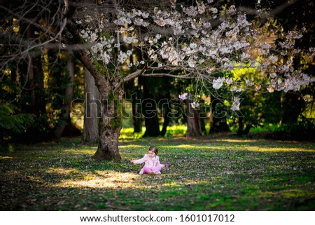 a small, beautiful girl with blue eyes,walking in the Park in a pink dress