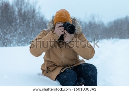 A man with a beard in the winter forest is making photographs. 