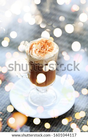 Irish coffee in an outdoor bar. Concept of St Patrick holiday. Holiday background. Irish national day. Warm tone. Vertical with festive bokeh lights